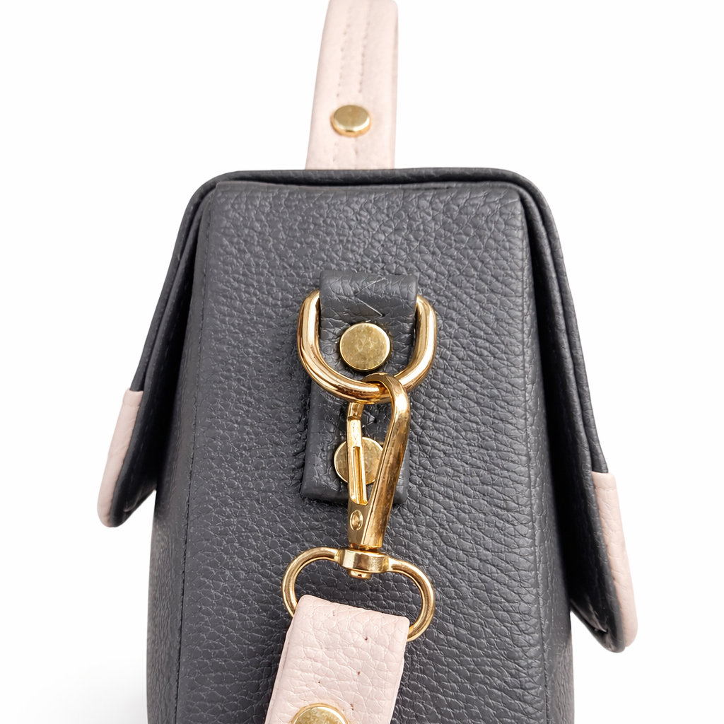 Gray leather bag with gold clasp and pink strap on a white background