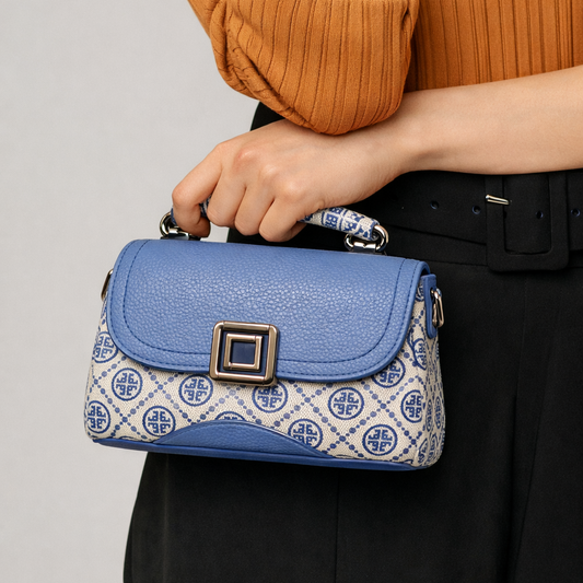 Person holding a blue handbag with patterned design against a neutral background